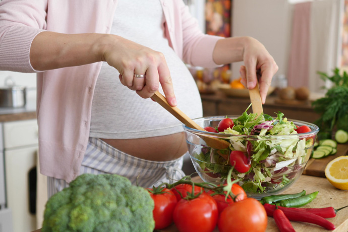 Mujer embarazada prepara ensalada saludable