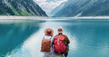 Dos personas sentadas frente a un lago.