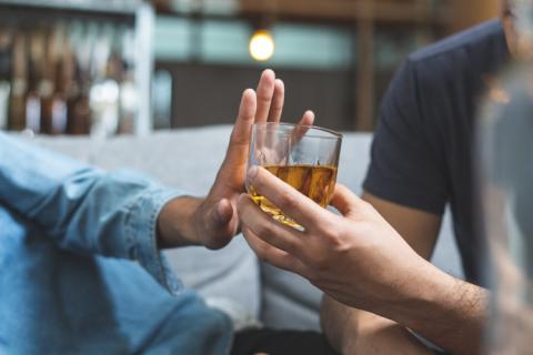 Persona rechazando bebida porque le sienta mal el alcohol.